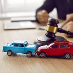 Two crashed toy automobiles on lawyer's table illustrating car insurance concept