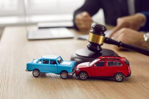Two crashed toy automobiles on lawyer's table illustrating car insurance concept