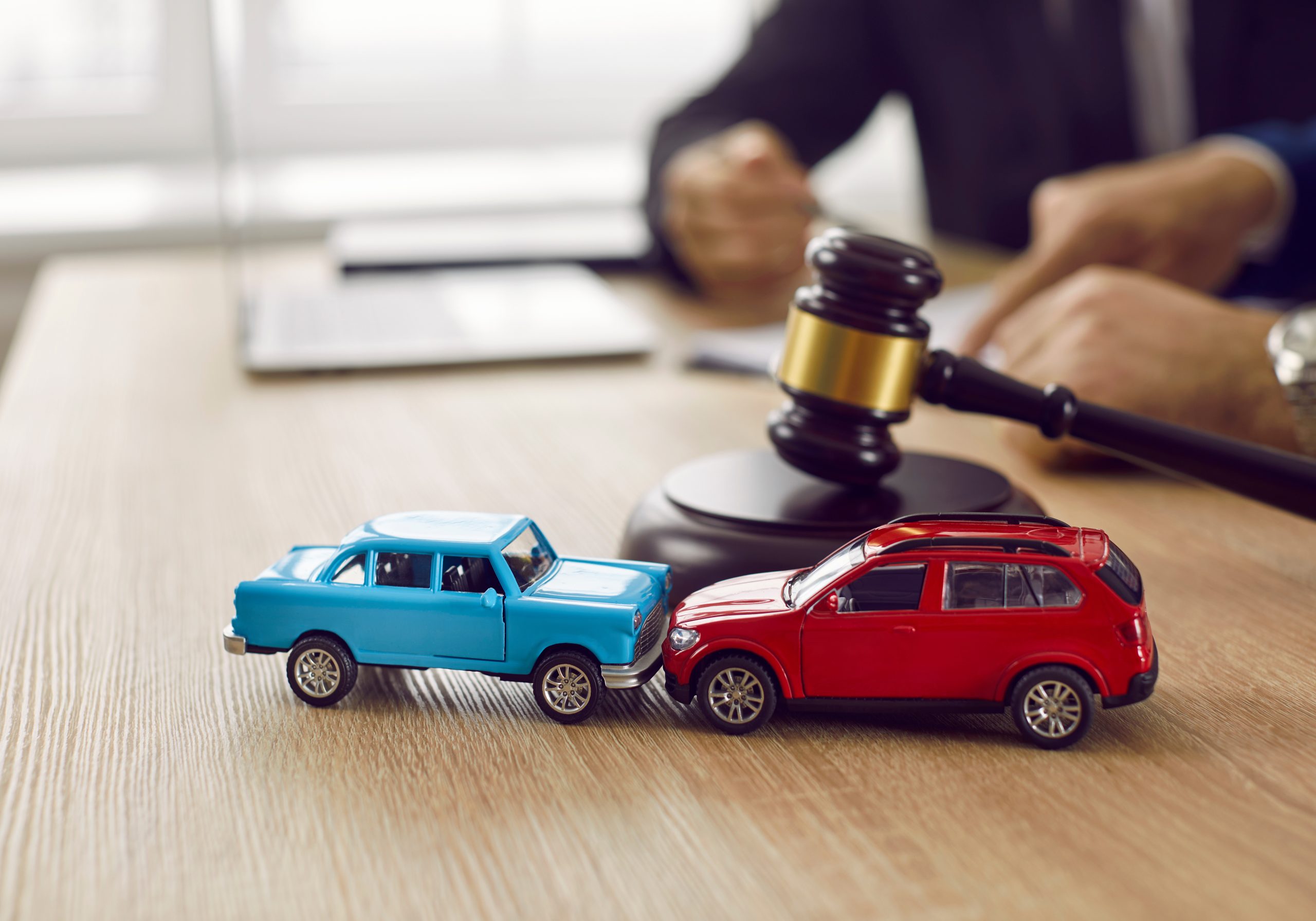 Two crashed toy automobiles on lawyer's table illustrating car insurance concept